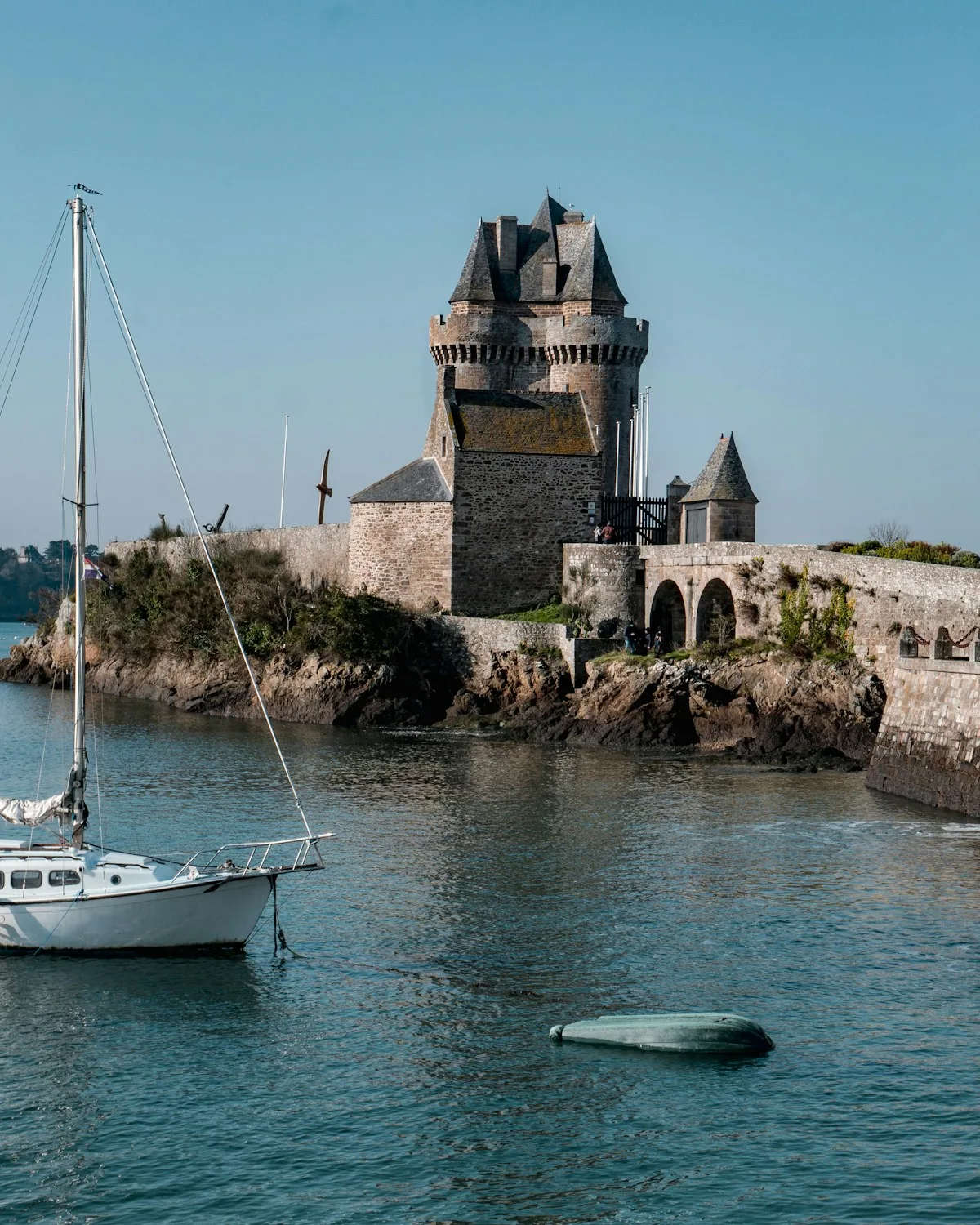 La Tour Solidor de Saint-Malo au bord de la mer, sous un ciel bleu, avec un voilier
